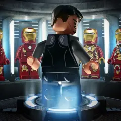 Tony Stark w swojej zbrojowni, otoczony przez różne wersje zbroi Iron Mana. To scena z gry LEGO Iron Man.