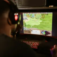 Gracz w słuchawkach z czerwonym podświetleniem gra w strategiczne gry survivalowe.