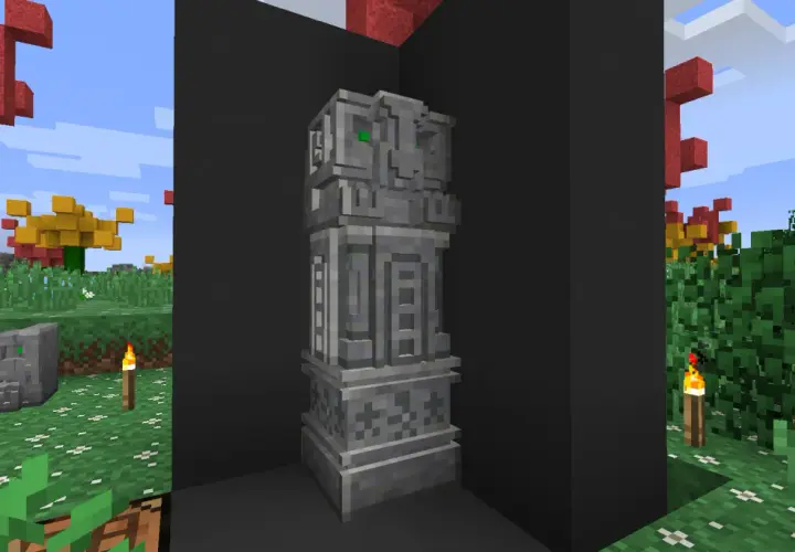 Kamienny monument z zielonymi oczami, jakby wyrzeźbiony dłutem i dłutkami. W tle jesienne drzewa i trawa.