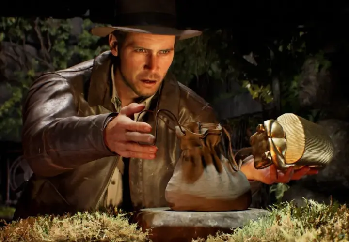 Indiana Jones i wielki krąg: archeolog z kapeluszem i skórzaną kurtką trzyma złoty artefakt w kształcie skarabeusza i skórzaną sakiewkę.