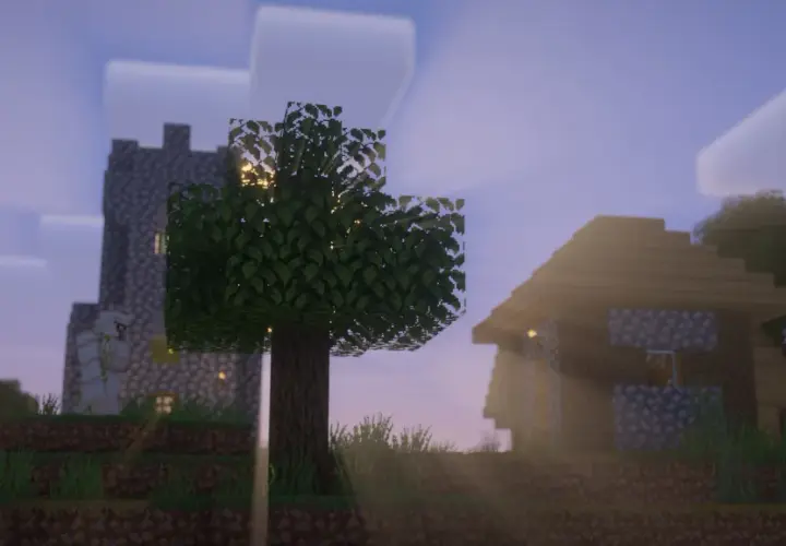 Wioska w Minecraft z vanilla plus shaders. Słońce przebija się przez drzewa, oświetlając kamienne domy i wieżę.