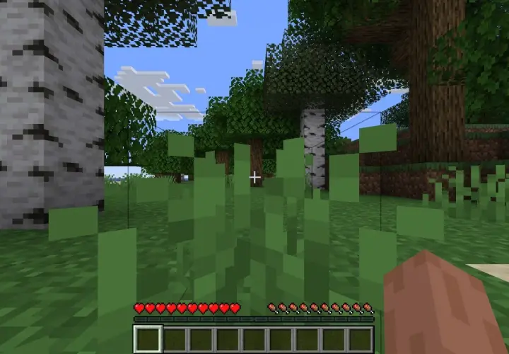 Wirtualny świat Minecraft. Gracz stoi wśród zielonych traw, widząc drzewa i niebo. Na dole ekranu pasek zdrowia i ekwipunek, gdzie widać jeden pusty slot.