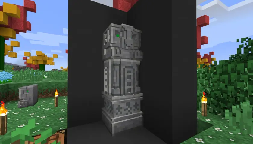 Kamienny monument z zielonymi oczami, jakby wyrzeźbiony dłutem i dłutkami. W tle jesienne drzewa i trawa.