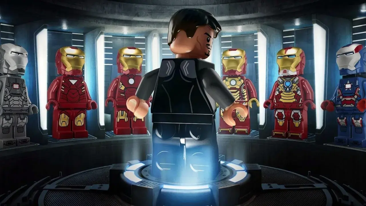 Tony Stark w swojej zbrojowni, otoczony przez różne wersje zbroi Iron Mana. To scena z gry LEGO Iron Man.