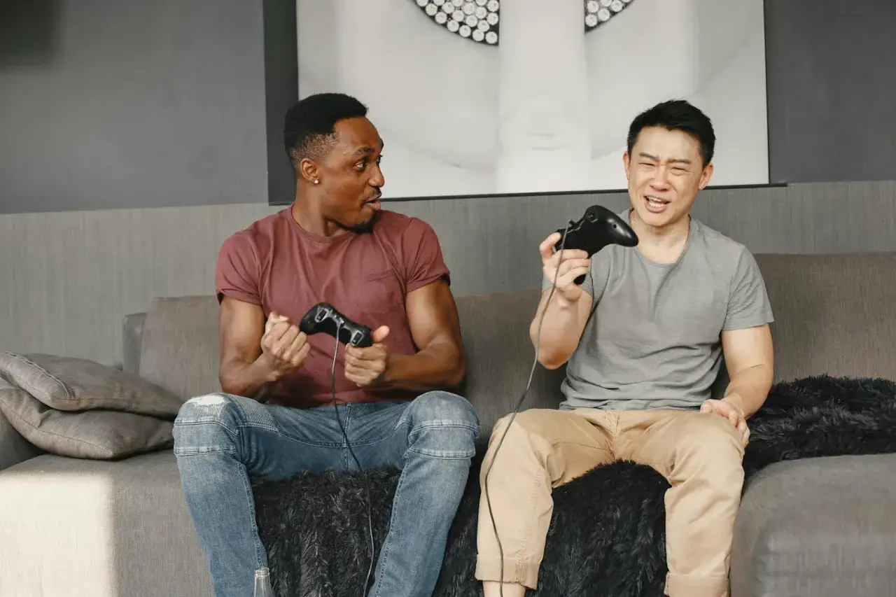 Dwóch mężczyzn gra w gry kooperacyjne na Xboxie, wyrażając emocje.